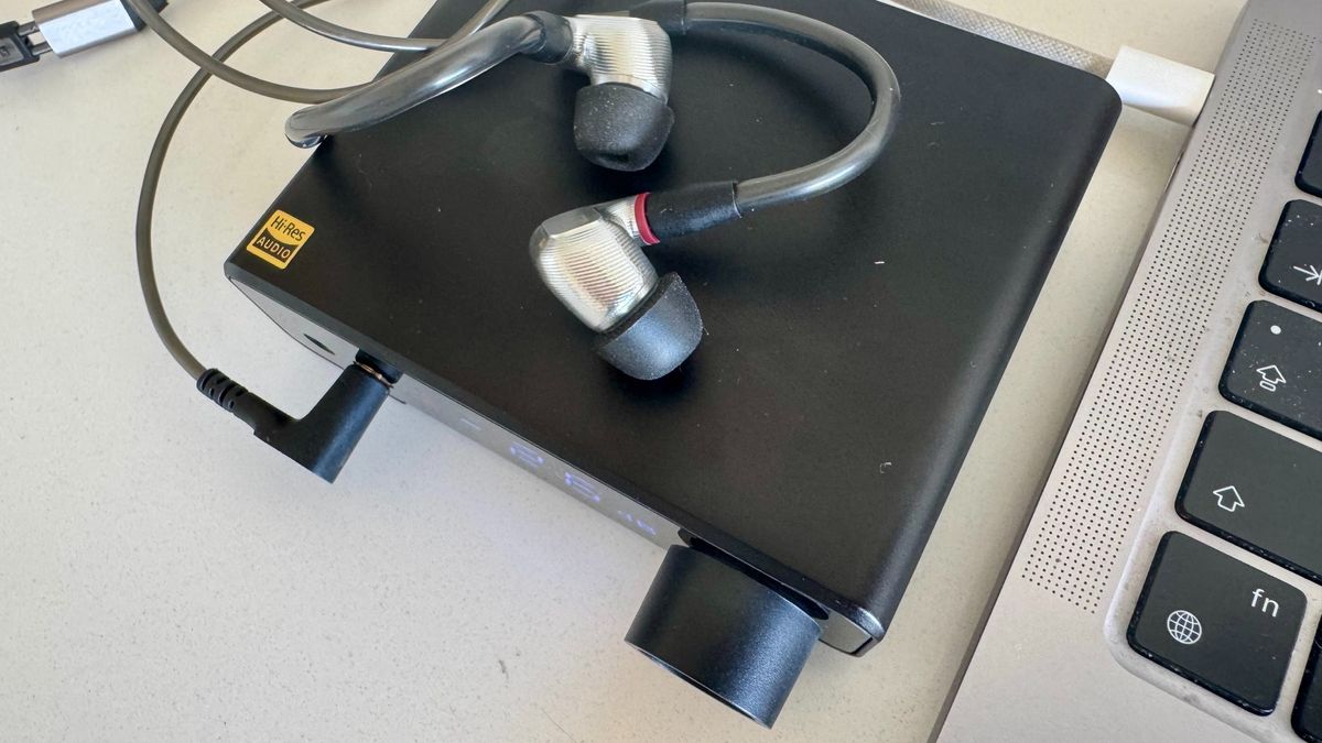 A birds eye shot of the Topping DX1 II DAC, next to a laptop and on a white surface