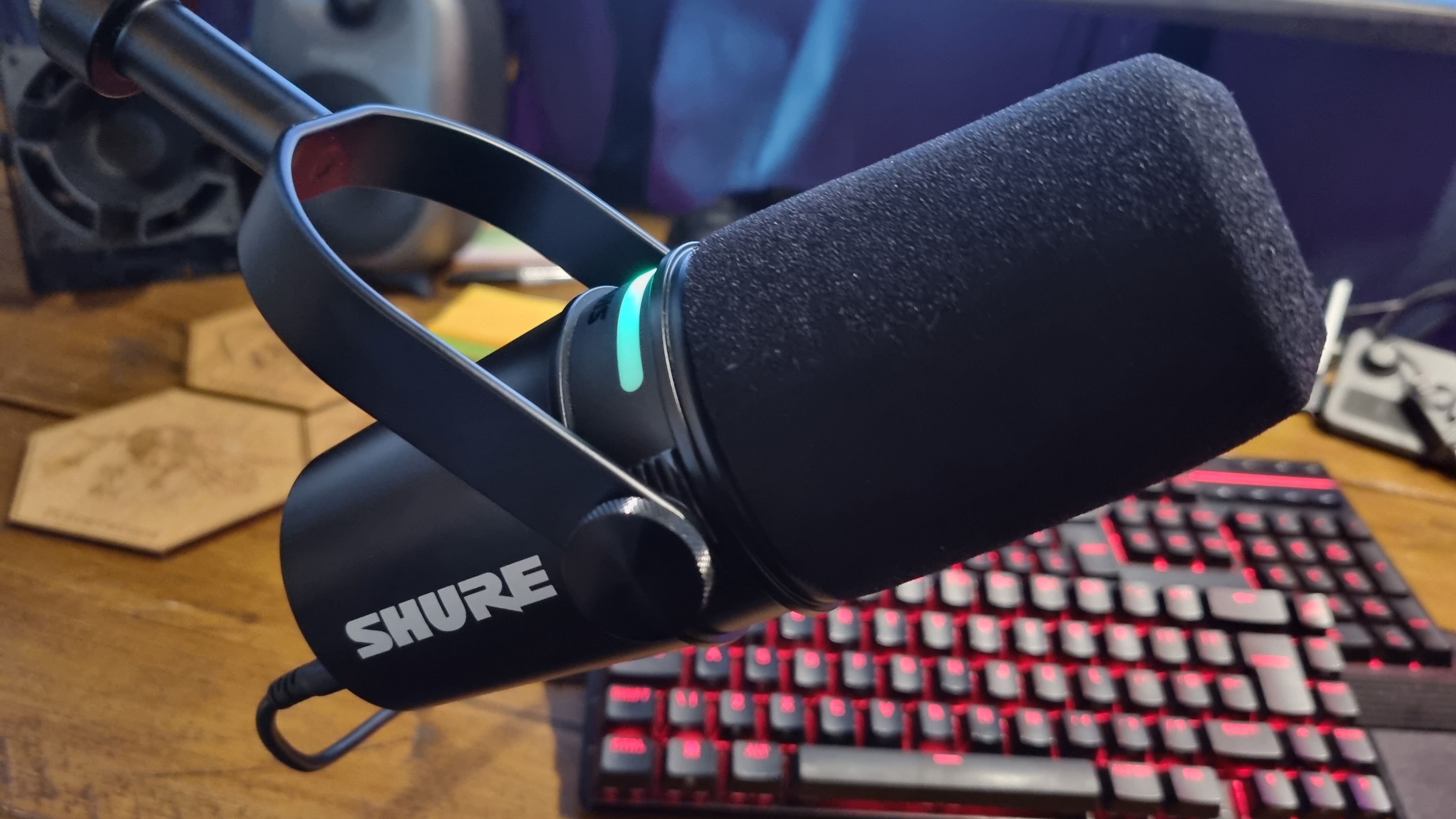 The Shure MV7 Podcast Microphone, on a boom arm, in front of a PC gaming setup