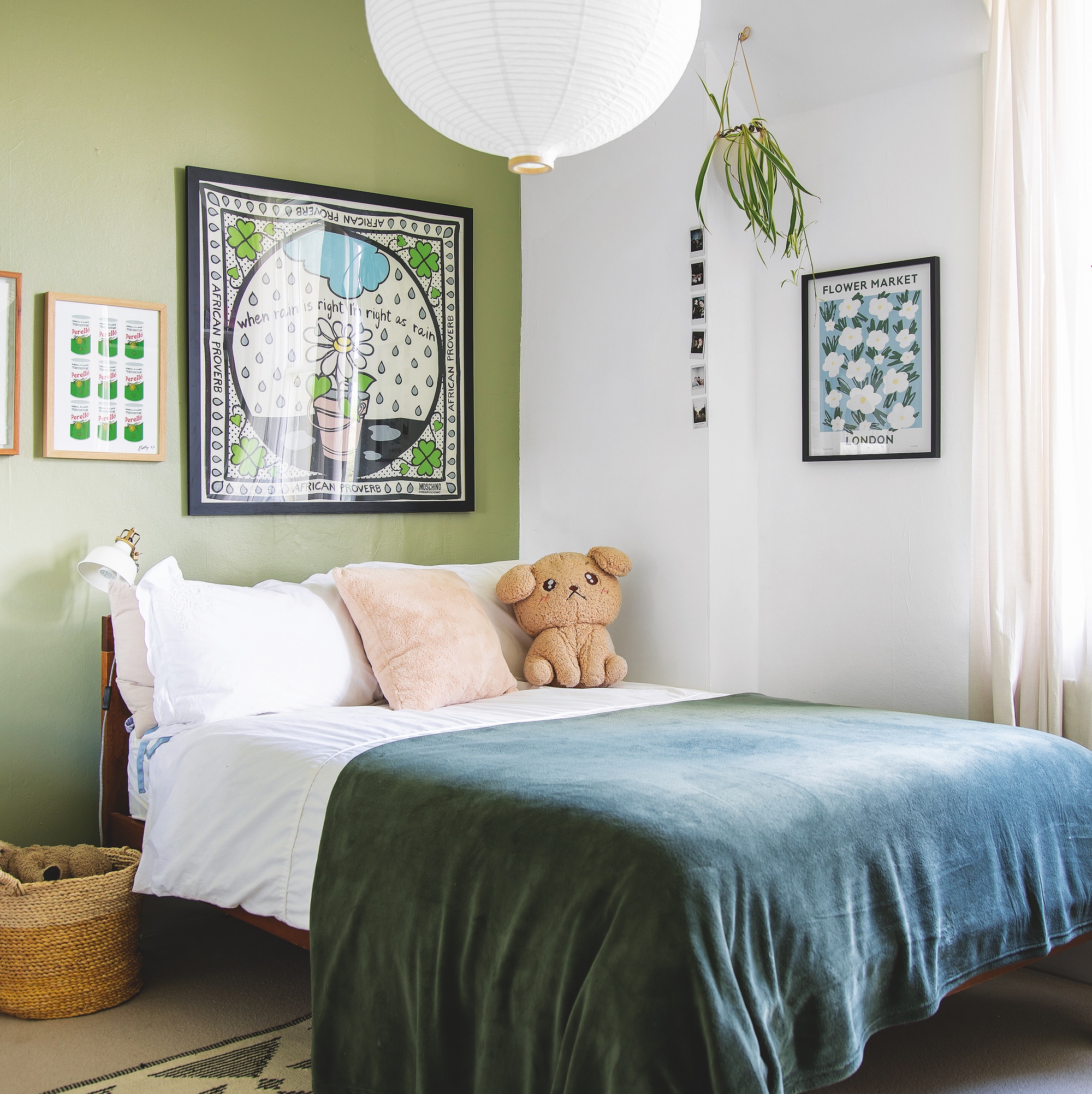 bedroom with green painted feature wall above bed with framed artwork