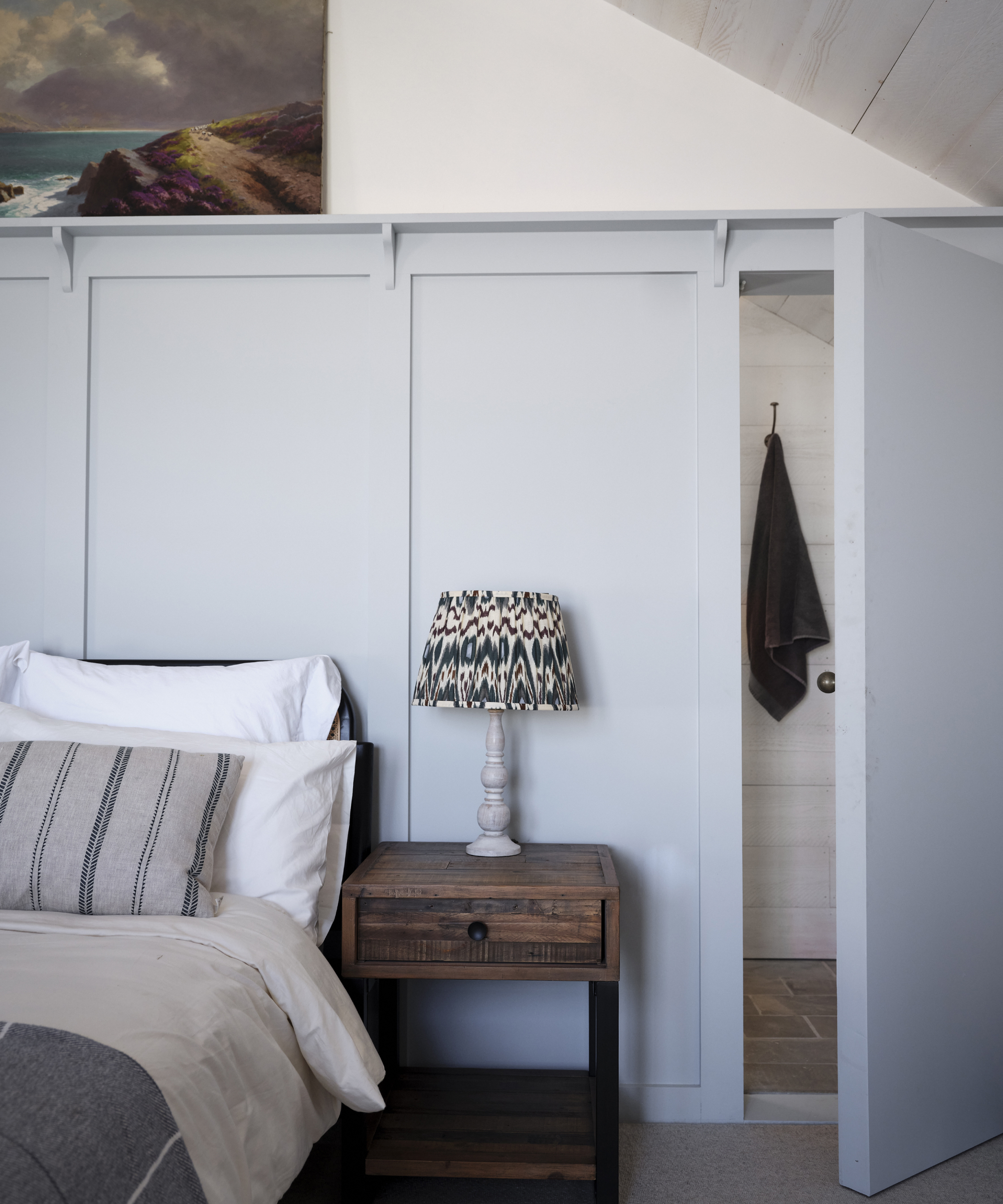 hidden door in pale blue panelling built behind bed