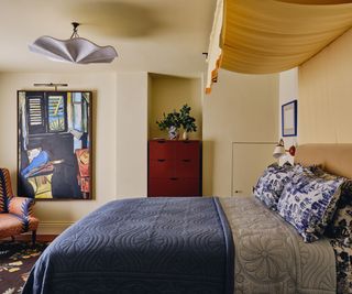 soft butter yellow painted bedroom with a yellow fabric bed canopy and a blue chintz fabric covered bed and bedding