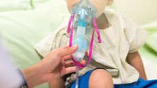 A young boy inhaling medication with inhalation mask.