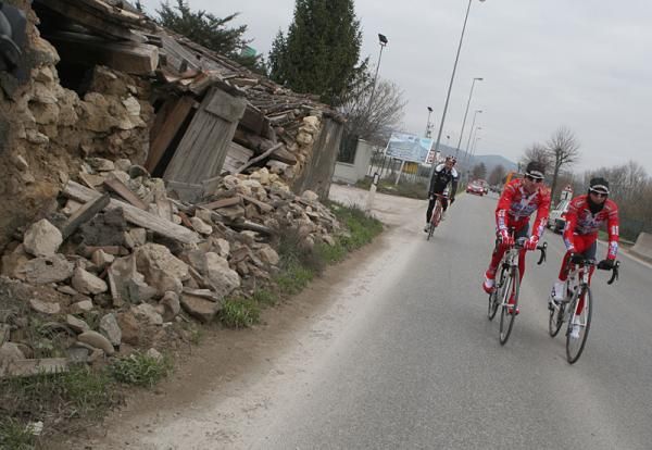 Riders pass destroyed buildings outside L'Aquila