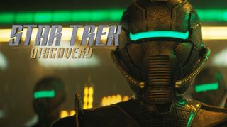 promo image for the show "star trek: discovery," showing a closeup of a bronze-colored space helmet with a green line where eye slits would be