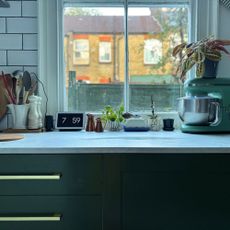 Green kitchen cabinet with gold drawer handles and white countertop