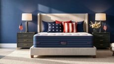 BedStory mattress on a grey bed in blue bedroom with matching black nightstands to either side with white lampshades.