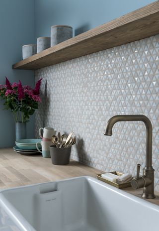 a tiled backsplash with small triangular tiles in a kitchen with open shelving