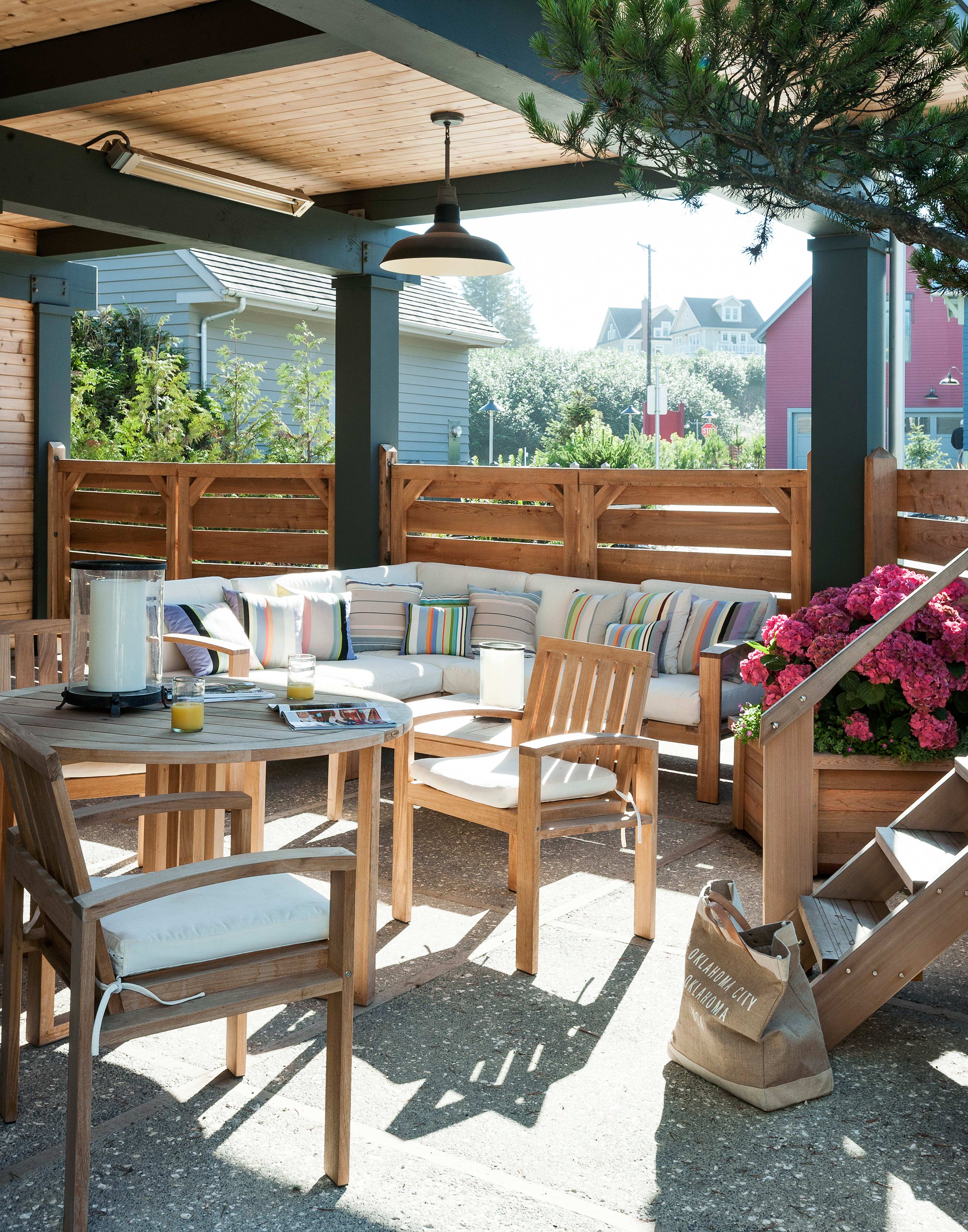 Roofed terrace area with wooden garden furniture and throw cushions