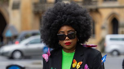 Black woman with natural textured hair wearing blazer covered in butterflies and sunglasses - gettyimages 2018778445
