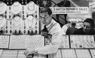 Jacob “The Jeweler” Arabo of Jacob & Co. Jacob “The Jeweler,” seen here in his Diamond District shop. A black and white photo of a man behind a jewelry counter.