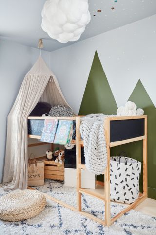 Kid's room with white walls and green mountain paint effect, wood bunk bed with canopy, white and black boho rug and cloud pendant light