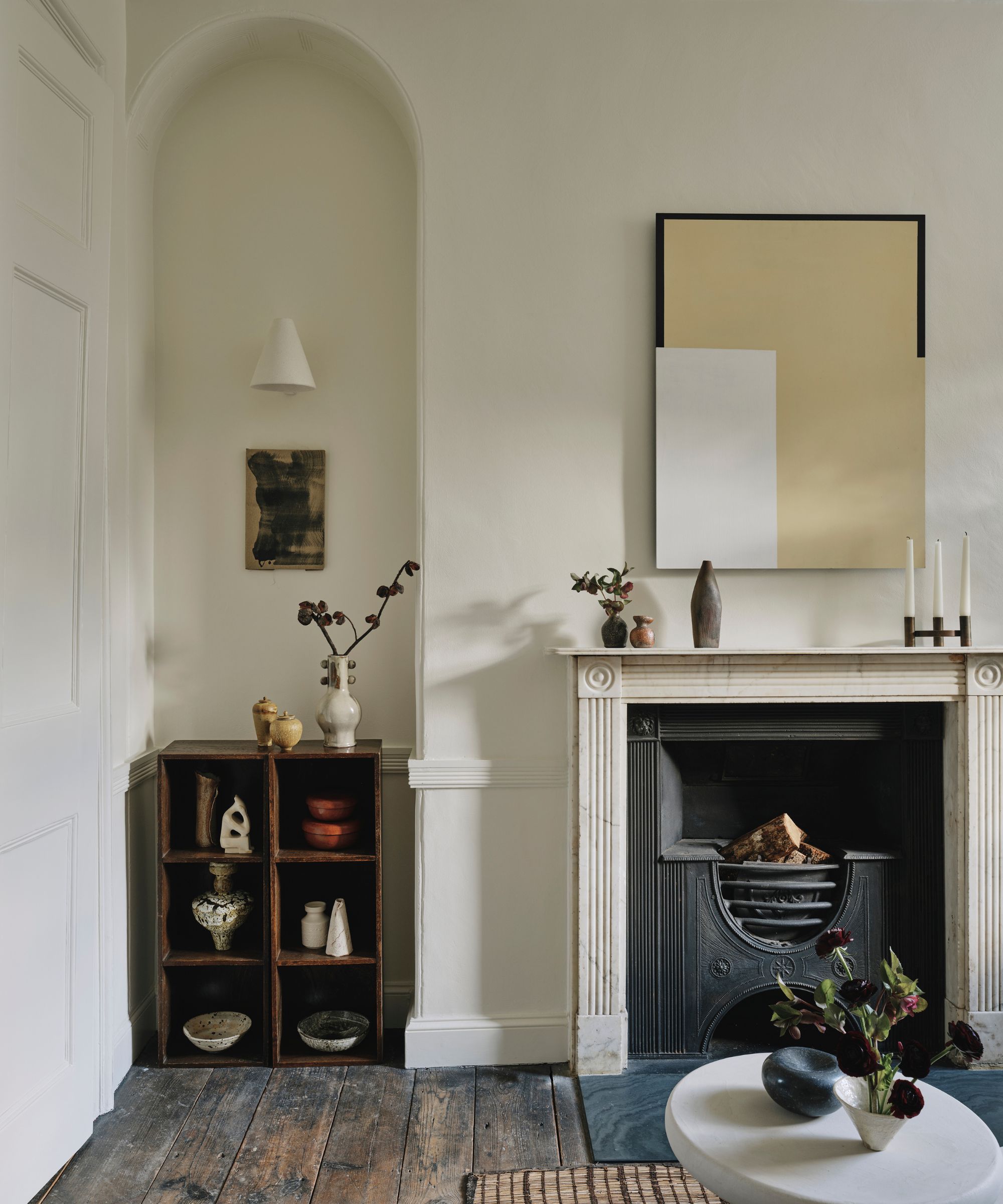White living room with stone marble fireplace and arched alcove with wooden storage within