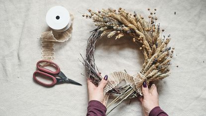 SOmoene making a fall wreath on a white table