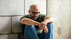 Frustrated man sitting on floor in front of concrete wall