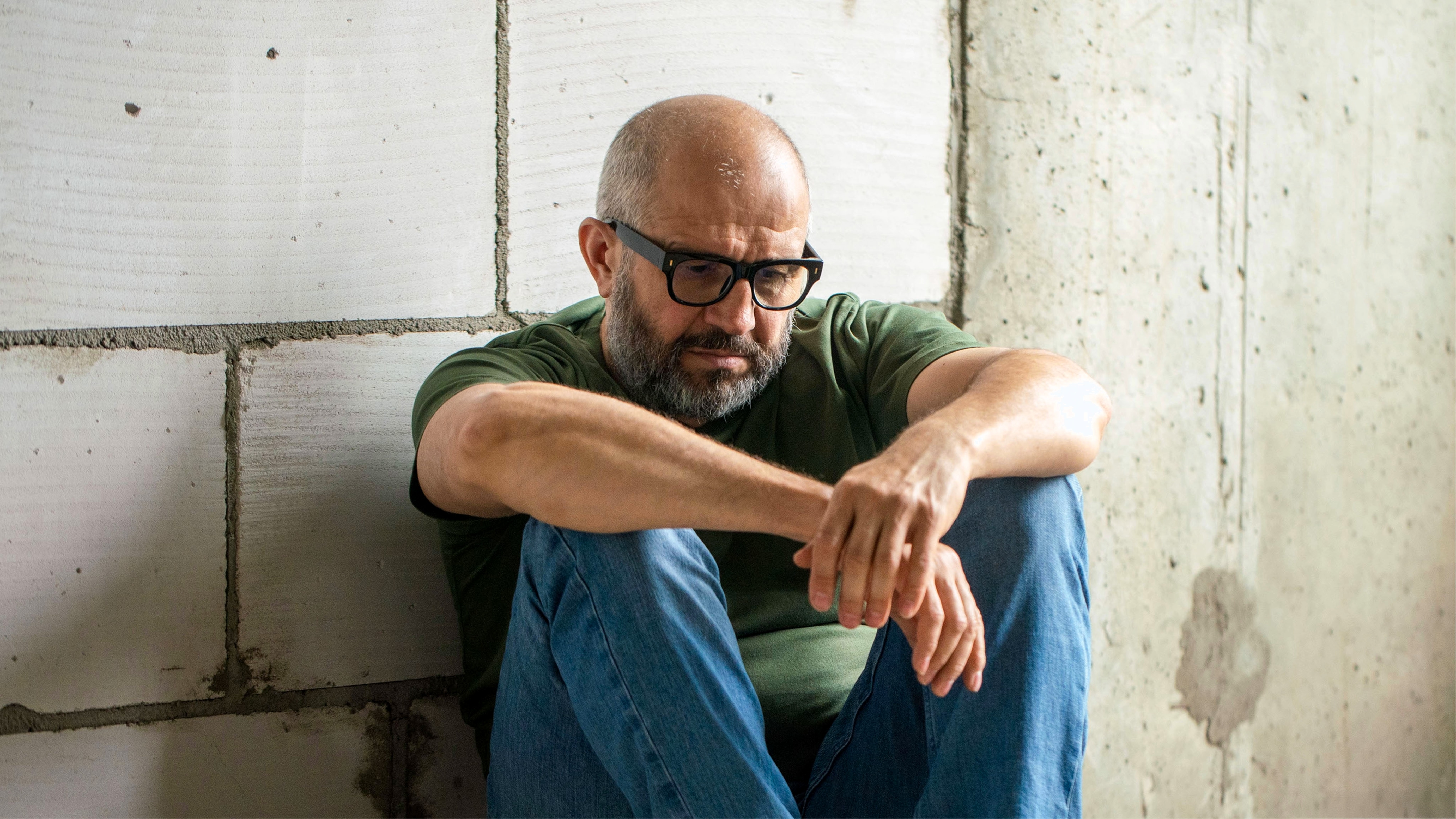 Frustrated man sitting on floor in front of concrete wall
