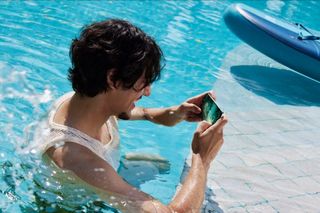 Man using a OnePlus 13 in a swimming pool with Aqua Touch 2.0