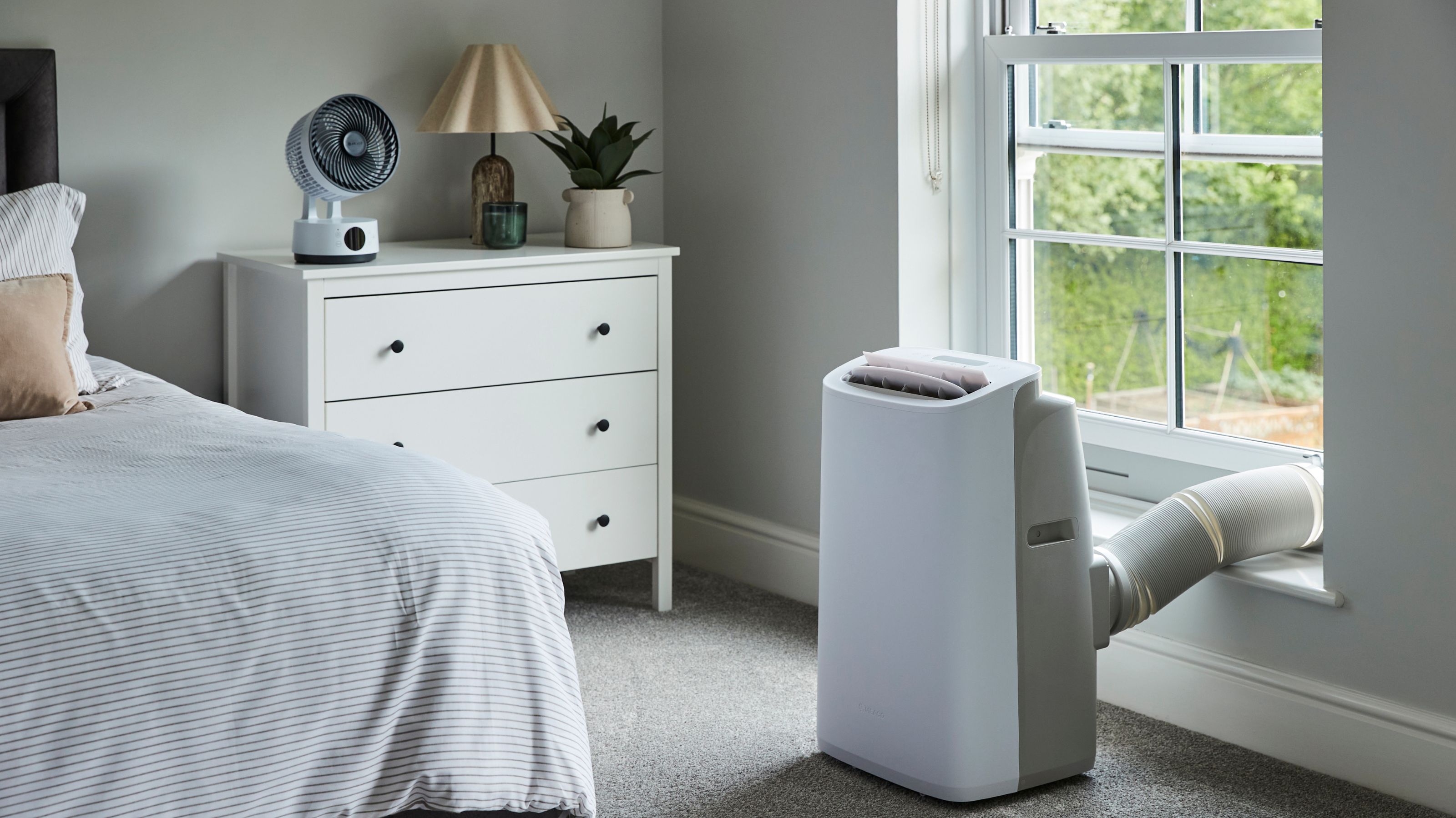 The new Meaco Cirro portable air conditioner vented out of a window in a neutral bedroom environment