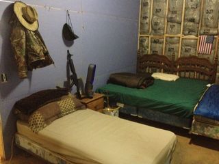 A view of the men's bunker in the Doomsday Castle. Notice the handgun and automatic rifle on the bedside table.