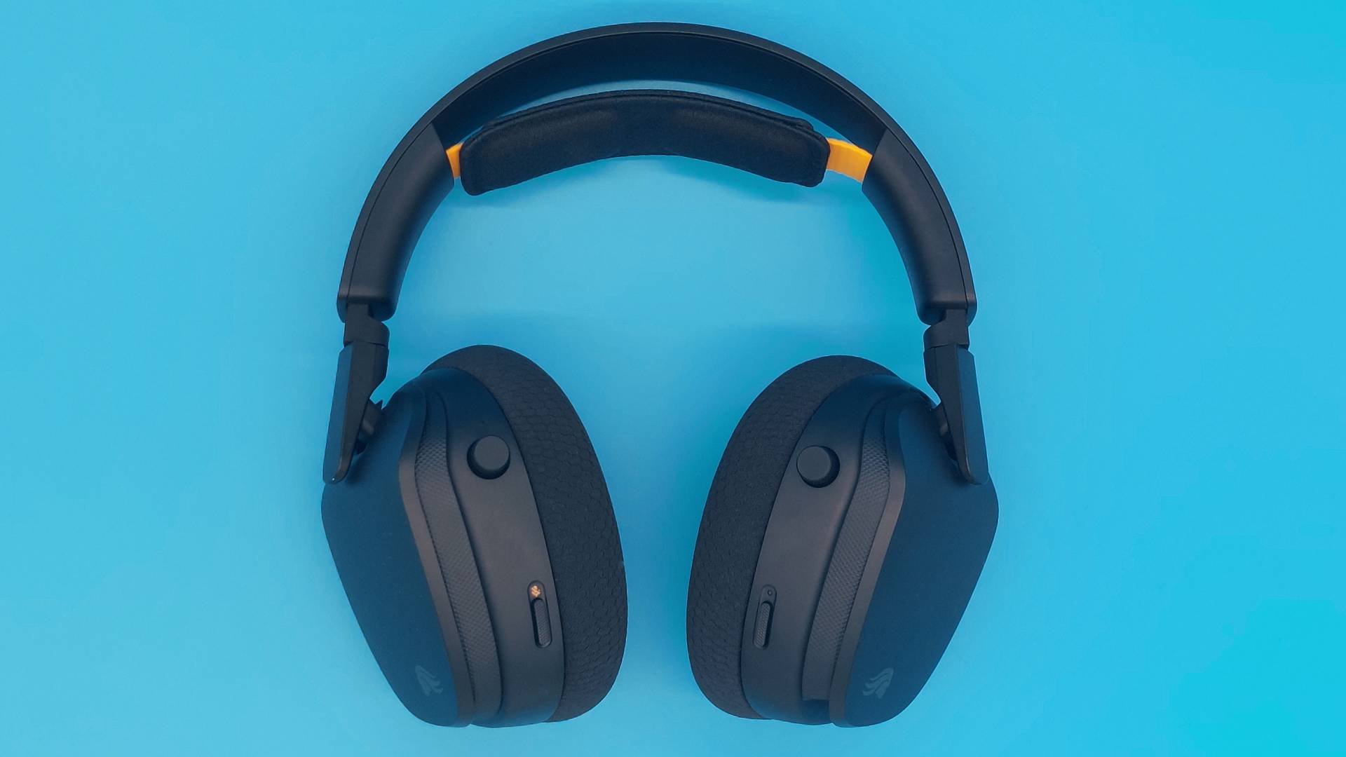 The GHS Wireless InfinitePlay seen from various angles on a blue background. This is a wireless gaming headset from Glorious. It is black all over, save for a few subtle orange accents.