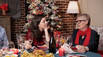 A younger woman and an older woman have a serious conversation during a holiday dinner.