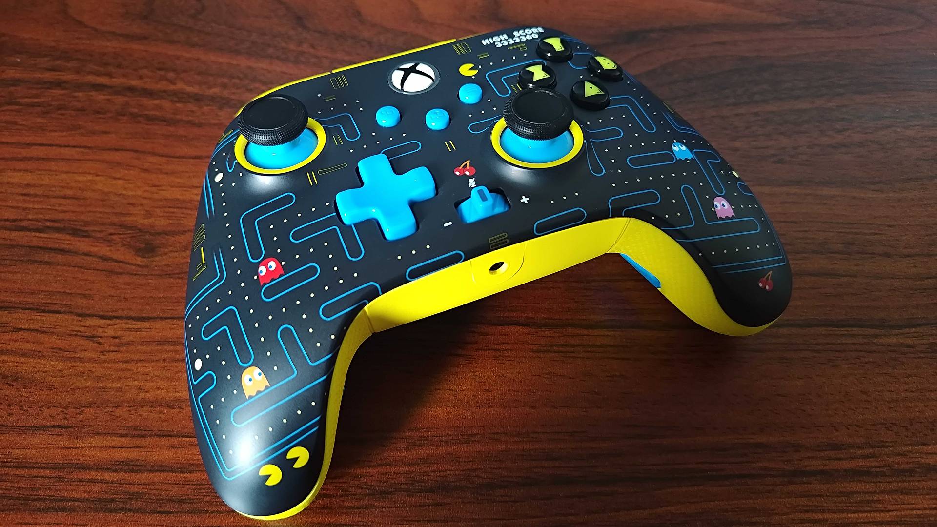 PowerA Pac-Man controller sitting on woodgrain desk.