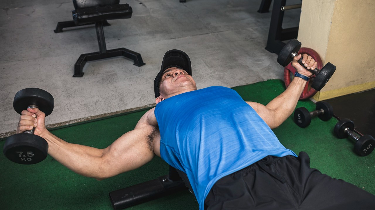 A man performs a chest flye with dumbbells