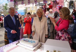 Linda Carter (Kellie Bright) and the EastEnders crew clap as The Prince of Wales and Duchess of Cornwall cut a cake