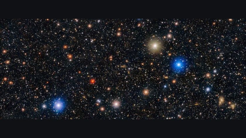 Image of space showing a black sky with hundreds of white dots and a few red, orange, gold and blue dots with halos of light surrounding them. 
