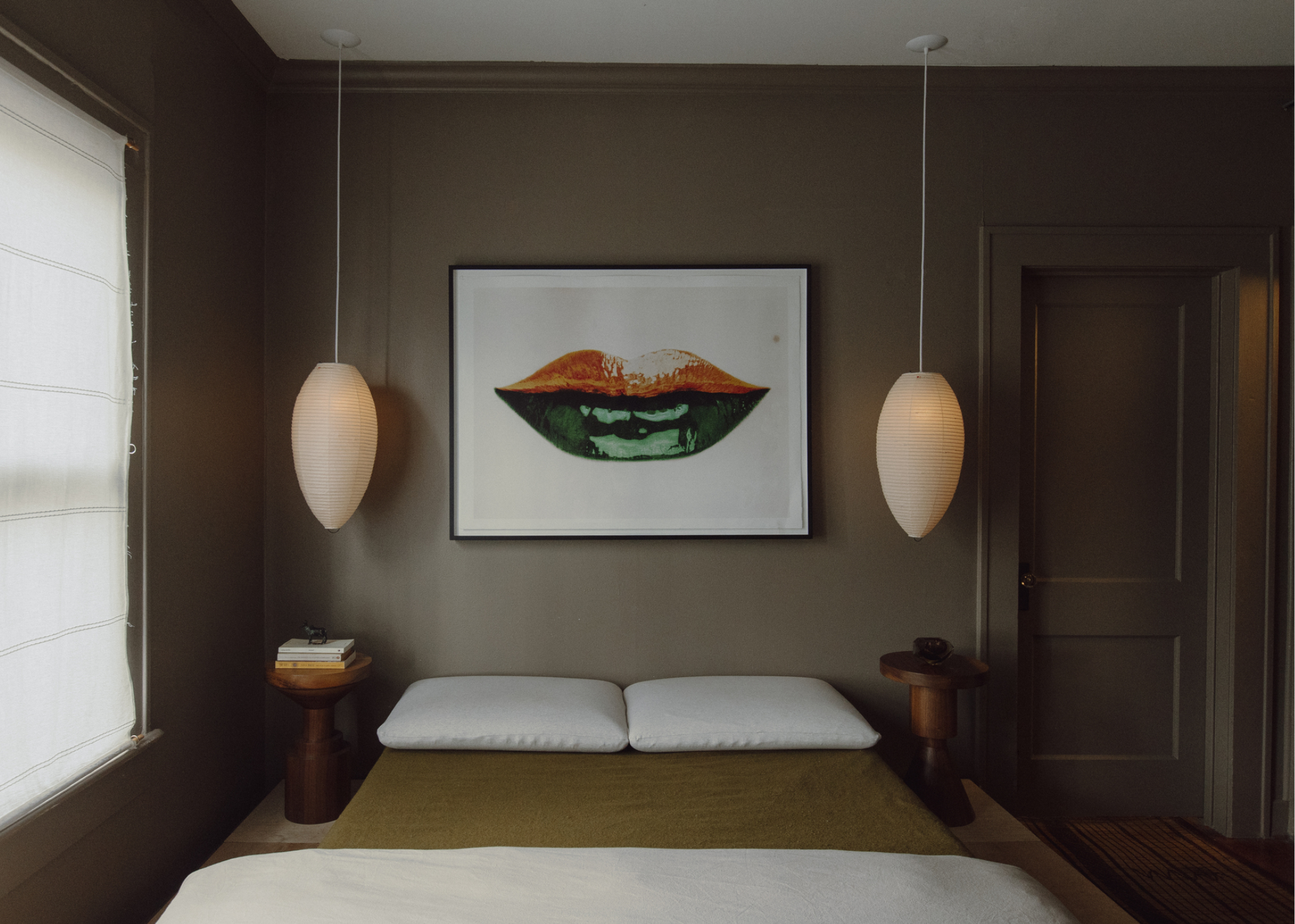 A dark small bedroom with pendant light either side of the bed