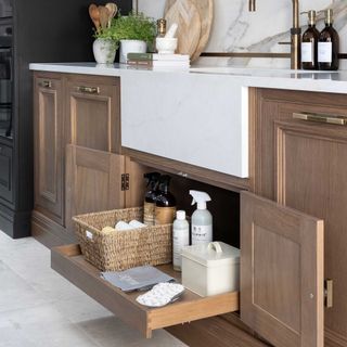undersink kitchen drawer in wooden kitchen containing cleaning equipment