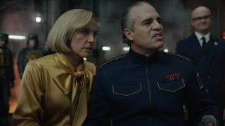 Toni Collette leans over to speak to a sneering, uniformed Mark Ruffalo in Mickey 17.