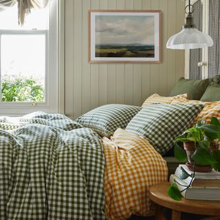 tiny guest room ideas, small bedroom with bed in corner, tongue and groove, checked bedding, artwork, pale green walls, side table, pendant lamp