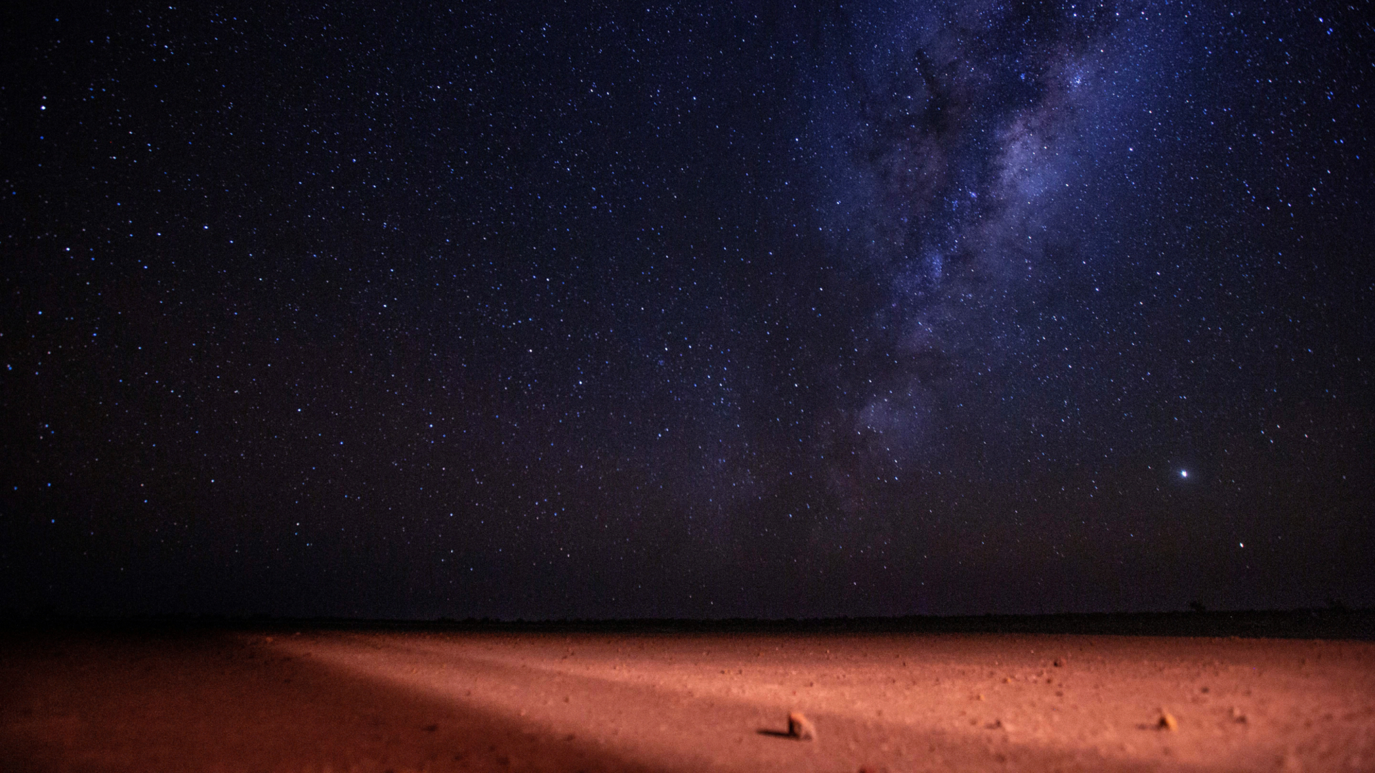 The Milky Way and stars shine over the Australian Outback at night.