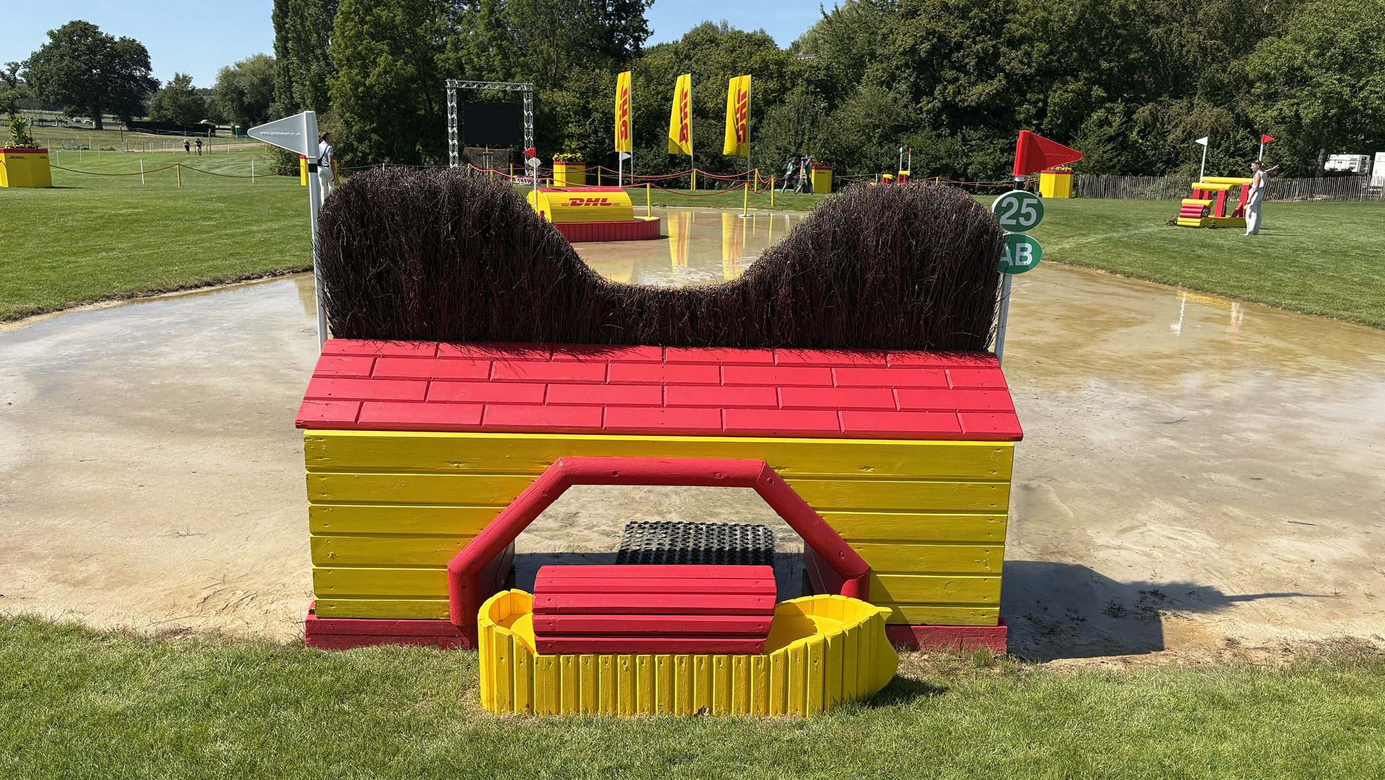 A yellow and red fence topped with brush into water on the eventing World Championships cross-country course