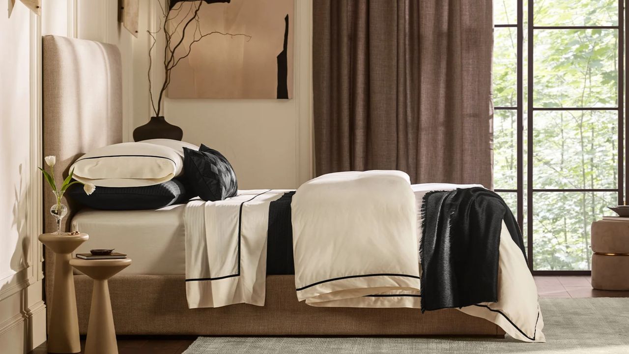 Black-and-white velvet applique bedding pictures in a neutral sunlit bedroom alongside contemporary art and wooden side tables