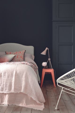 bedroom with black wall, charcoal wardrobe, grey bed, coral accents