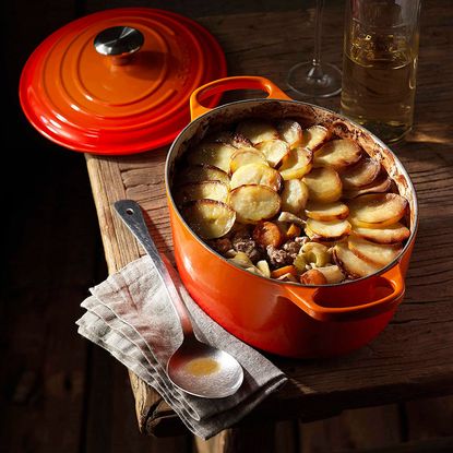 orange casserole dish with spoon on wooden table