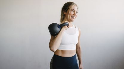 What size kettlebell should I get? Image shows woman carrying kettlebell on shoulder