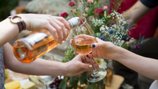 Woman pouring rose wine into a glass. 