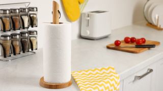White roll of paper towels next to yellow and white cloth on countertop