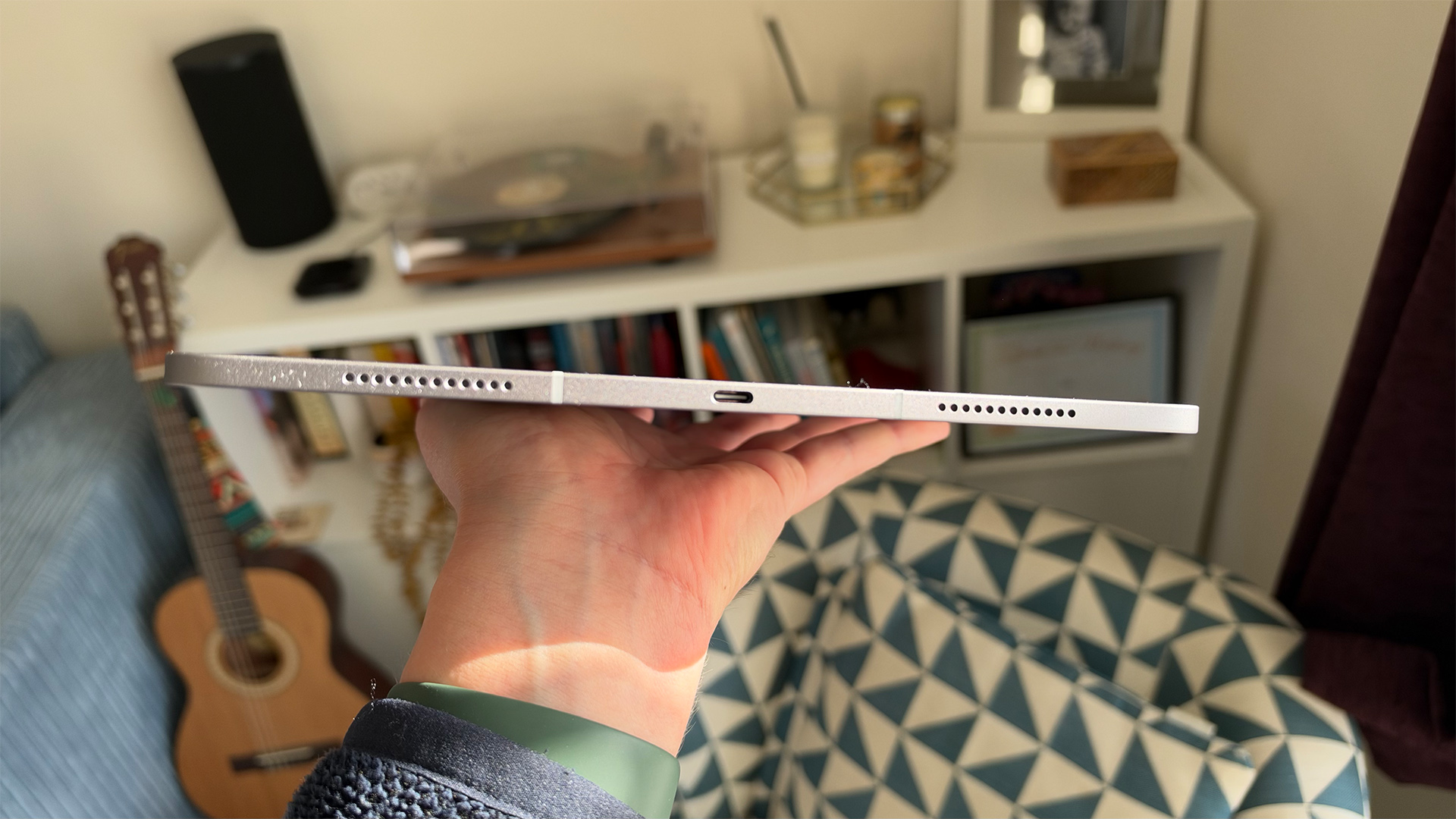 Apple iPad Air 13-inch (M4) tablet held in hand showing speakers and USB-C connection on edge of device