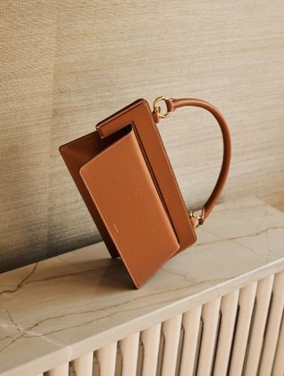 Tan leather bag stands on its side