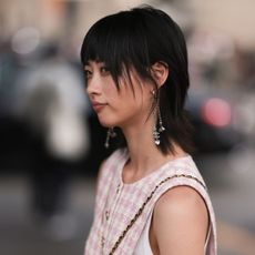 Fashion week guest looking away from the camera with short dark hair and a pink chanel dress