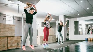 Three woman at the gym doing squat jumps