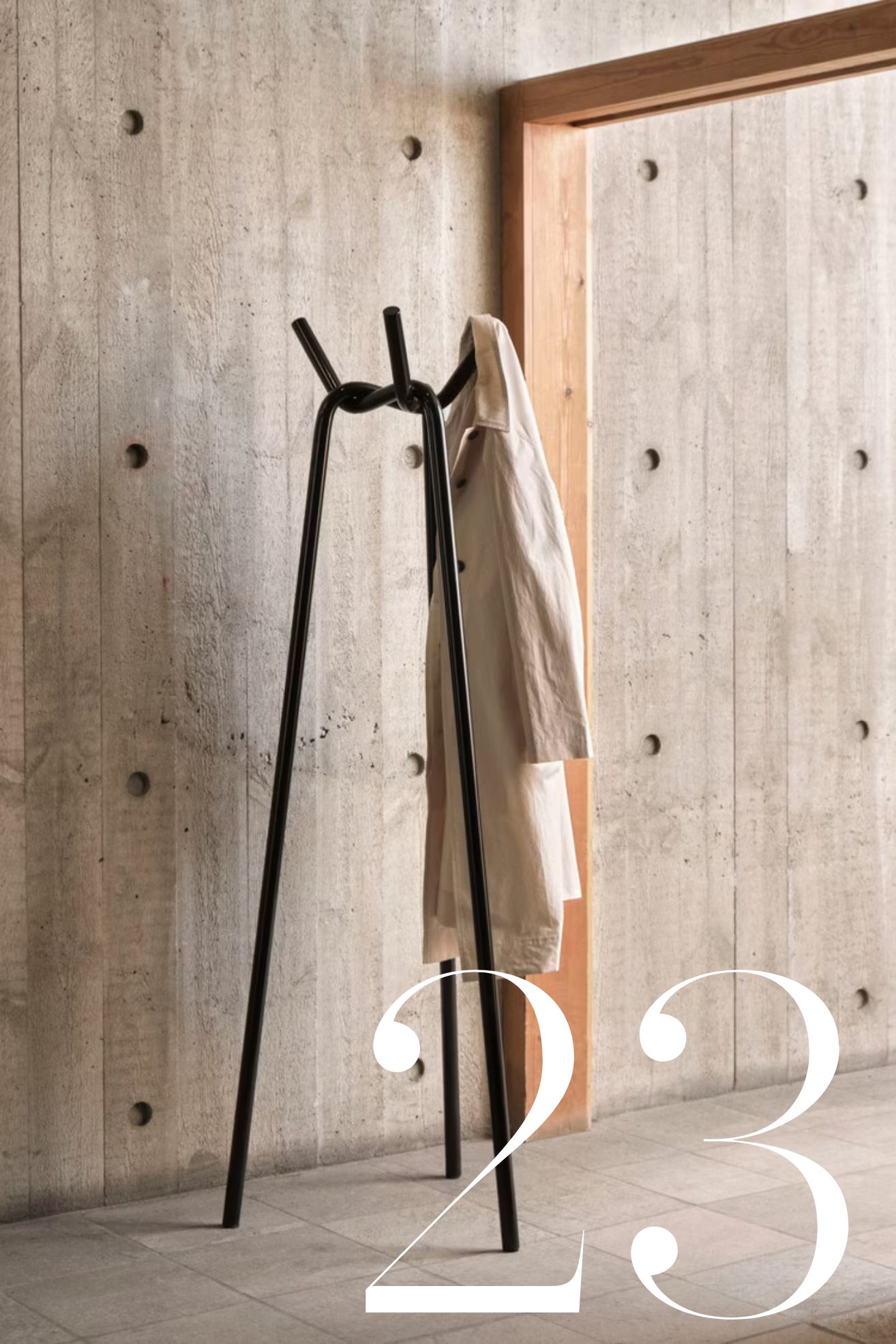 hay knot coat stand in hallway with concrete walls and timber doorframe
