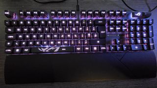 The Asus ROG Strix Scope II RX gaming keyboard photographed on a wooden desk.
