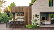 Outdoor kitchen attached to the house, with bar seating and wooden cladding around