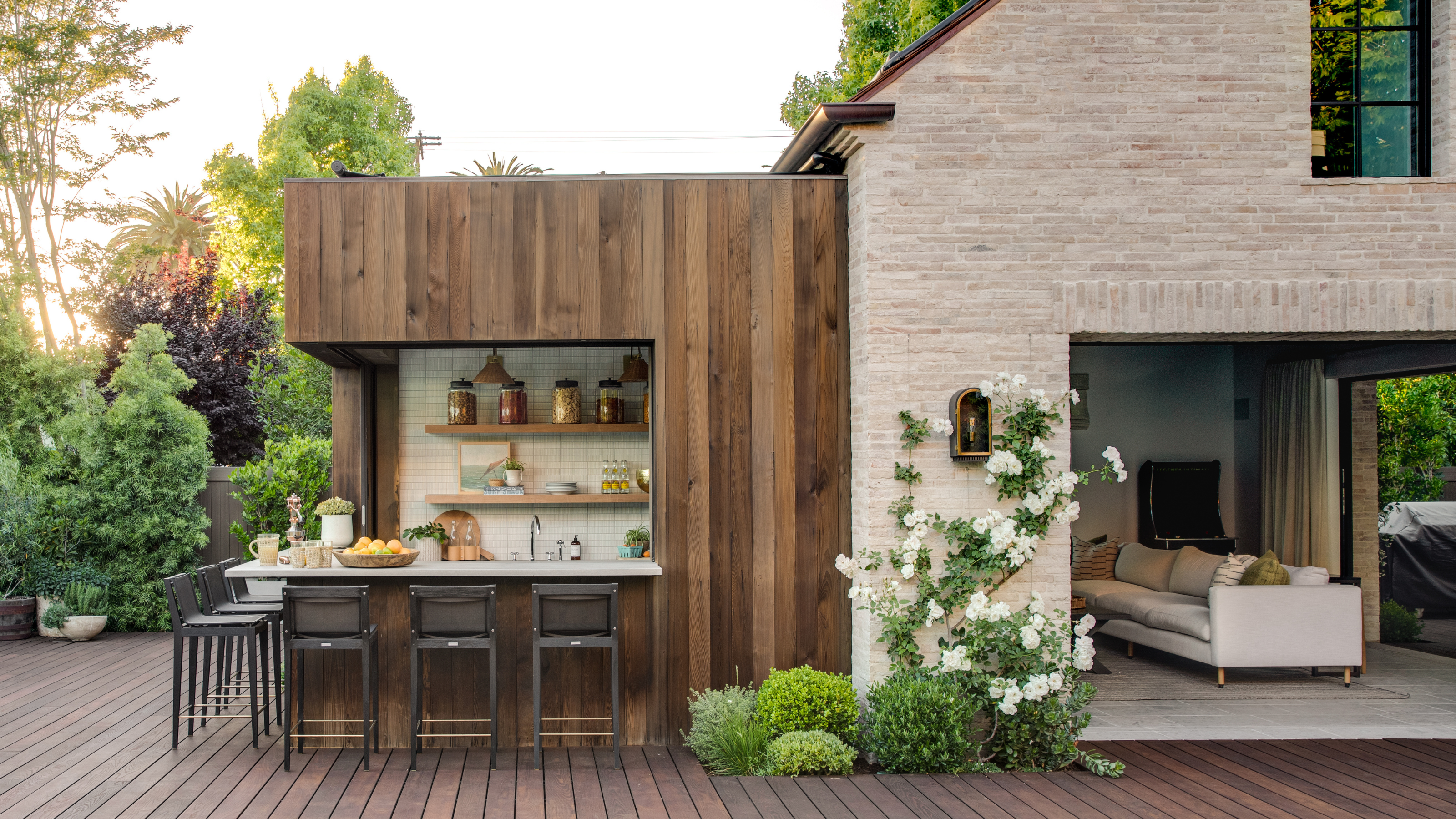 Outdoor kitchen attached to the house, with bar seating and wooden cladding around