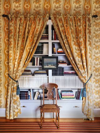 hallway with curtains and bookshelves and chair