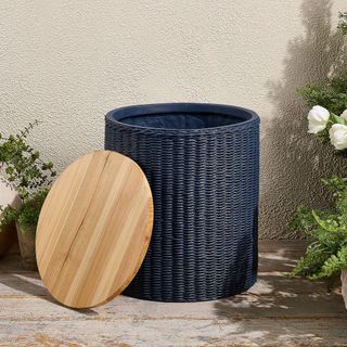 A woven storage table with a wooden lid on a patio